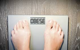 A person battling overweight/obesity on a scale. The scale reads OBESE
